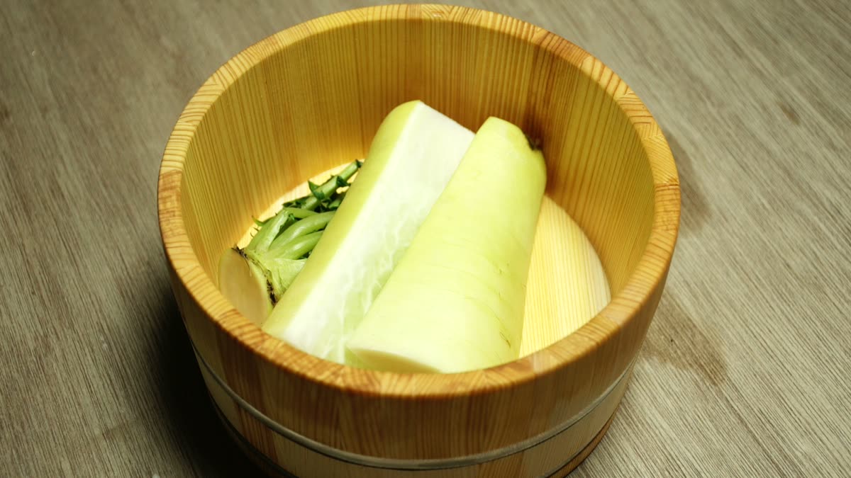 桶に入れた大根に塩をもみこむ