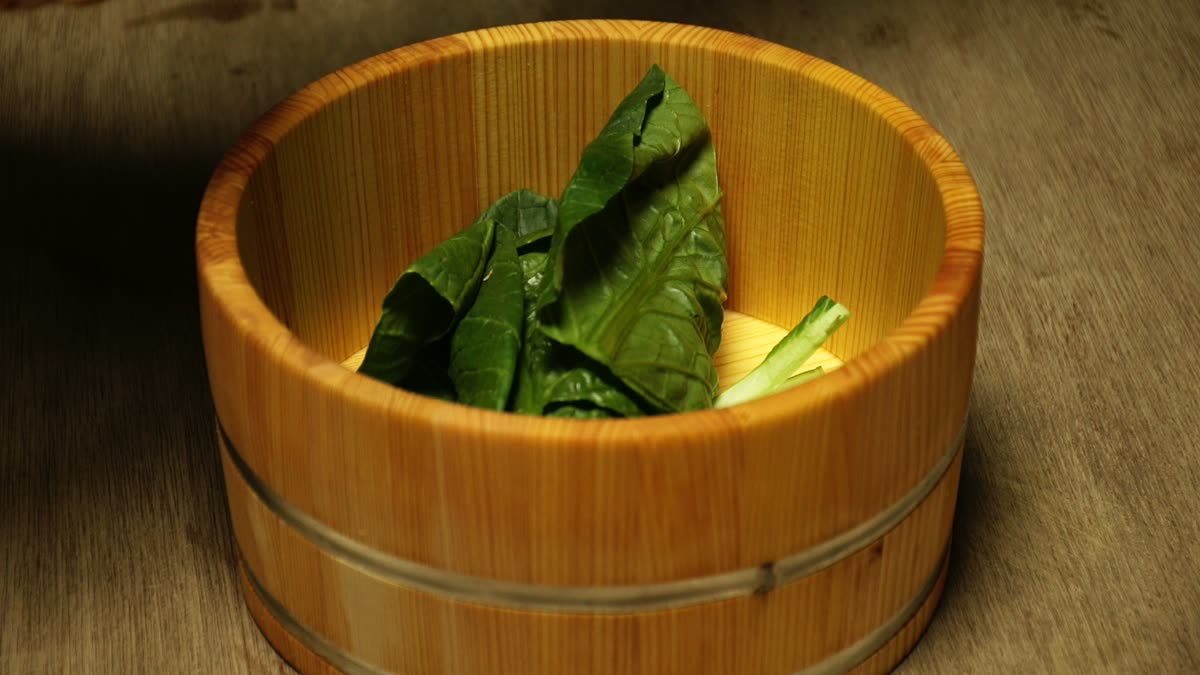 桶に小松菜を漬け込み塩をふる