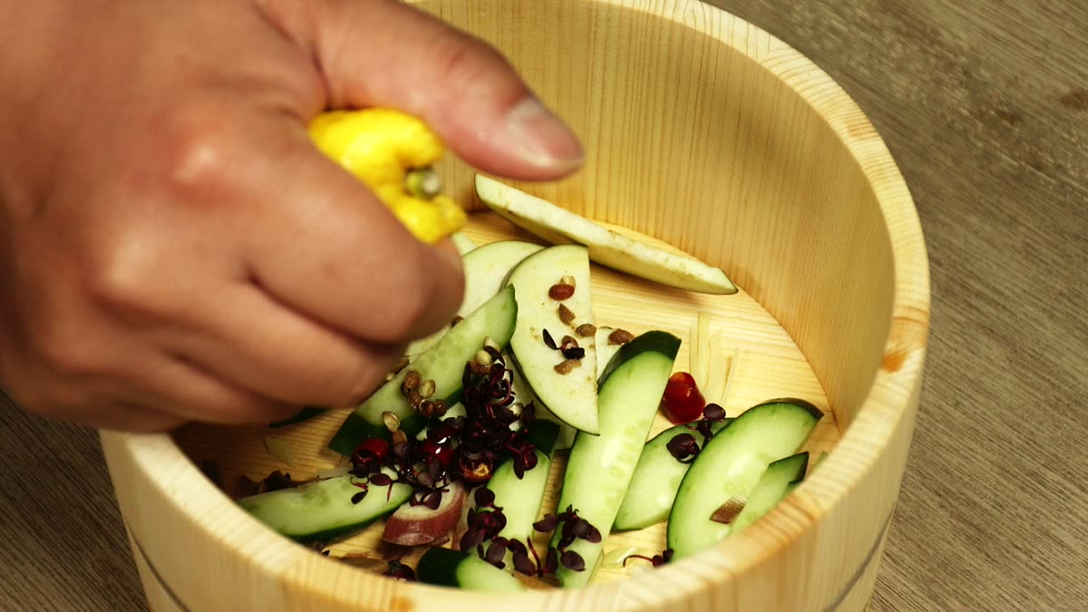 桶に入れた香味野菜の上から柚子を絞る