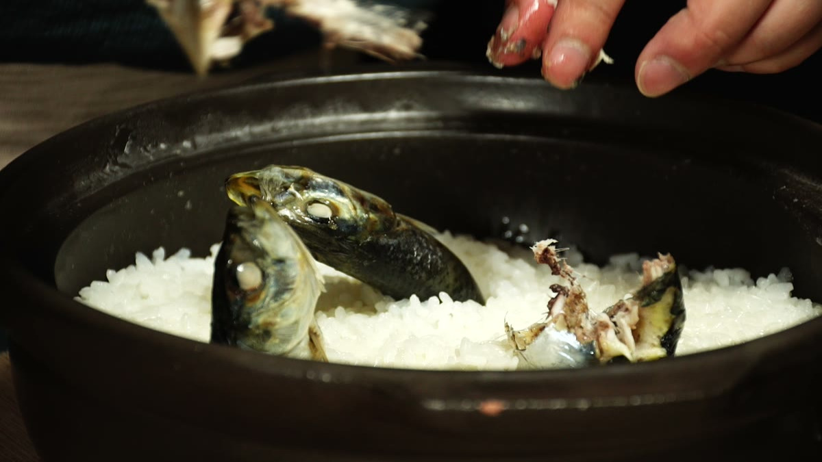 蒸らしたイワシの頭を指でつまみ、骨ごと引き抜いているところ