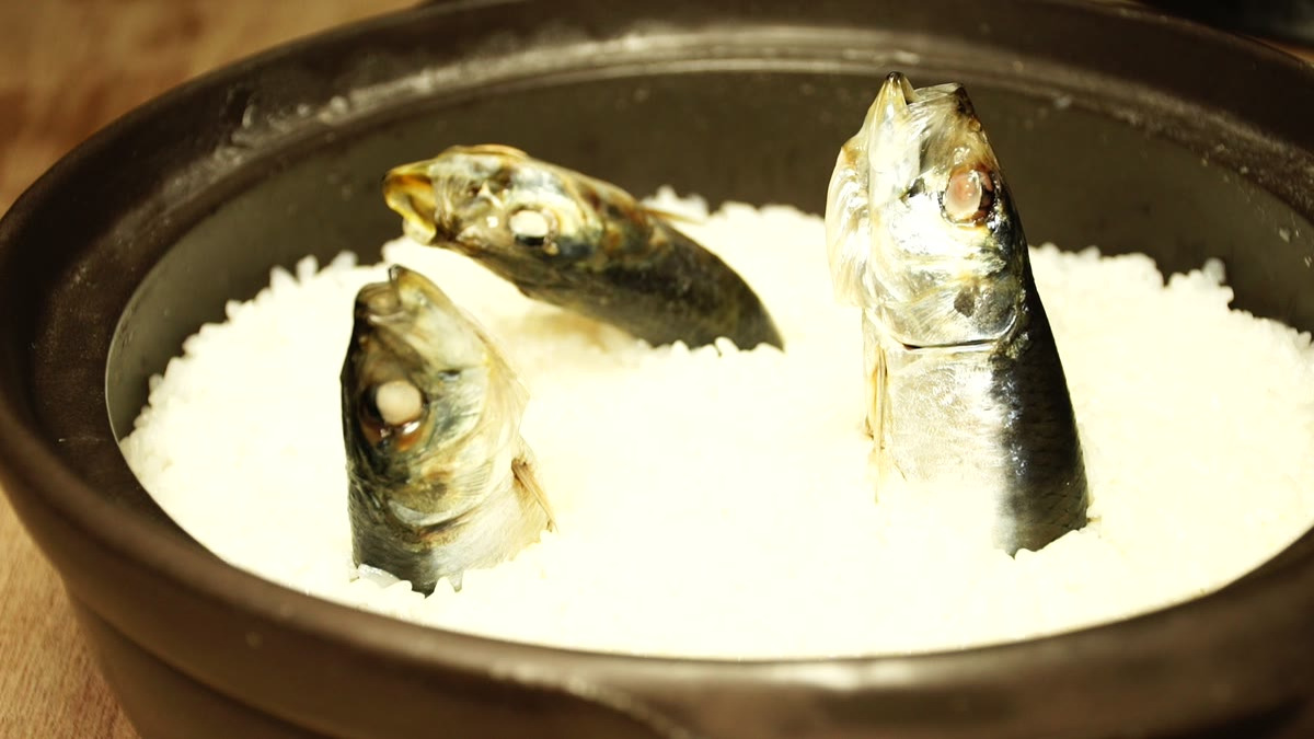 蒸らし終わり、白い飯からイワシが頭を出して立っている土鍋の中