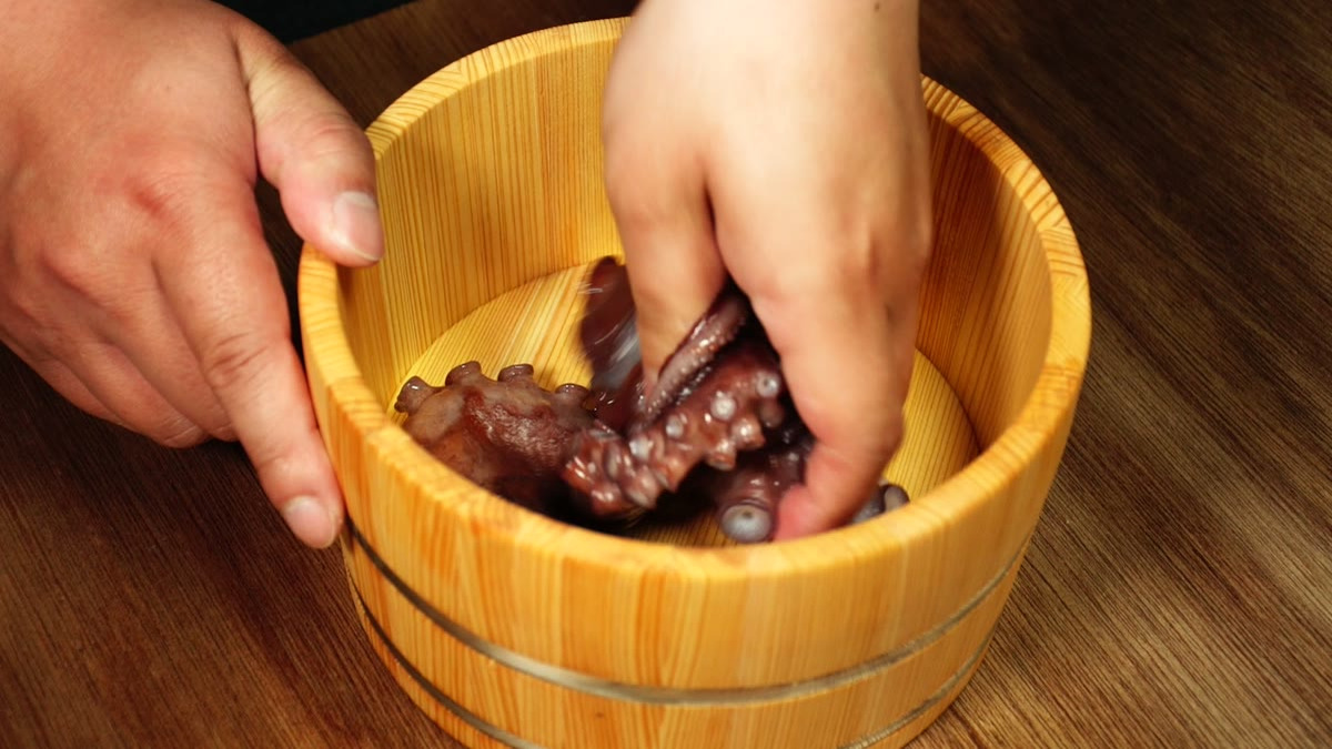 木桶の中で生タコを塩で揉み洗いしている手元