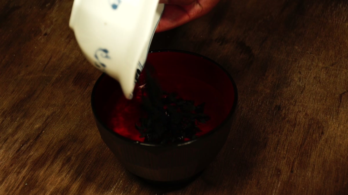椀に入れたわかめに、注ぎ口のある白い器から水を注いでいるところ