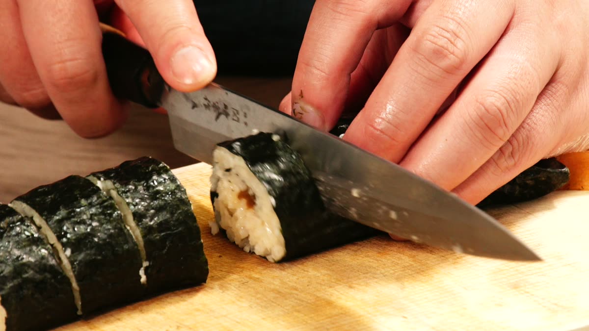 かんぴょうの細巻を包丁で切り分けるところ