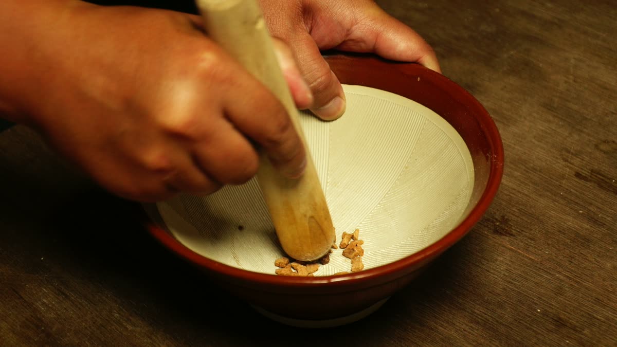 すり鉢とすりこぎで漢方を粉末にしていく手元