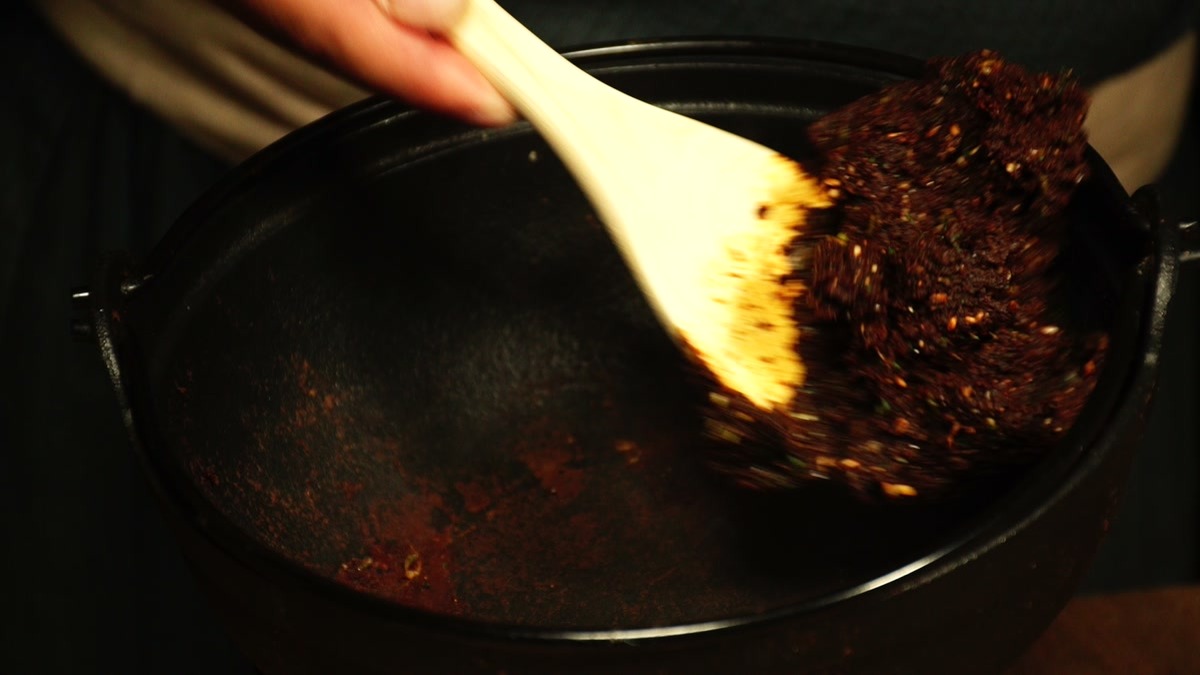 鉄鍋で豆味噌にすりごま・ネギ・大葉を混ぜて焼いていく手元