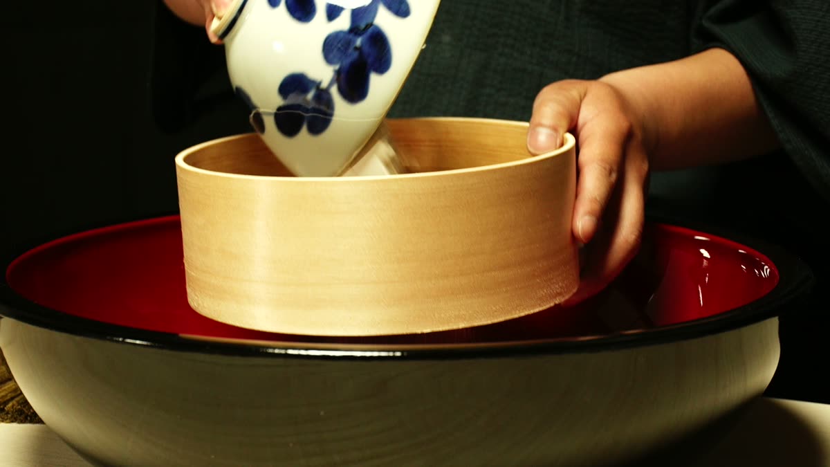 こね鉢に篩をかけながらそば粉を入れる