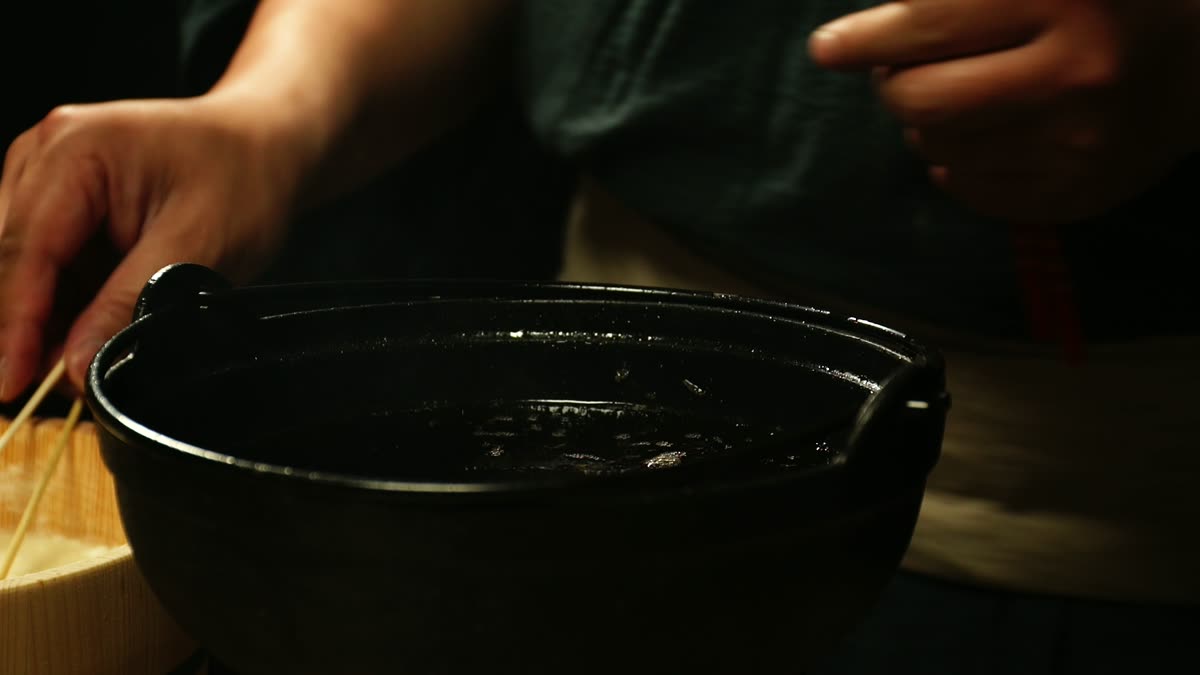 鍋で串に刺した天ぷらを揚げる