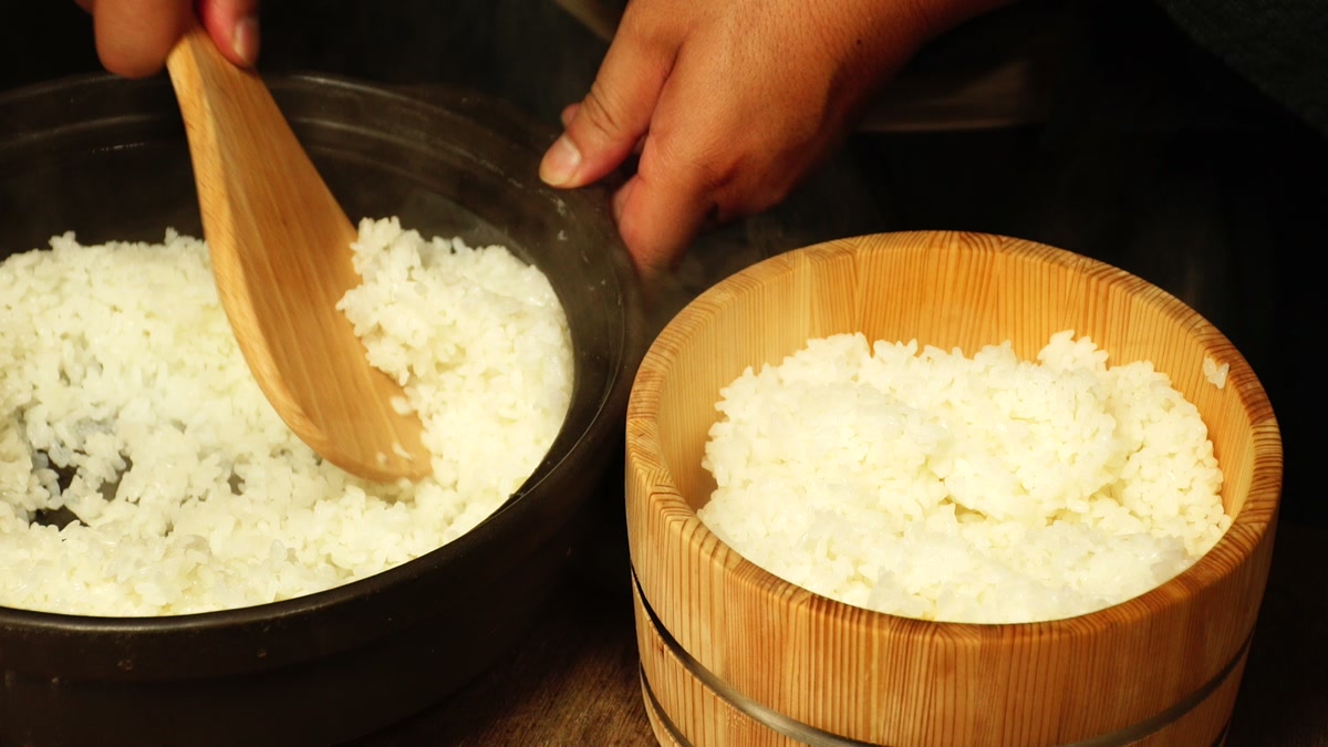 釜から炊きあがった飯をしゃもじで木のおひつへ移しているところ