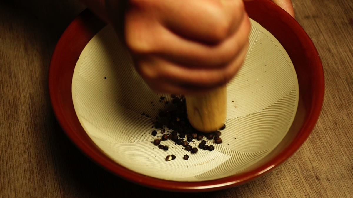 すり鉢の中で黒胡椒をすりこぎで潰しているところ