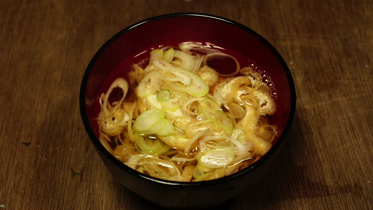 朱の椀によそったネギ汁。斜め切りのネギと油揚げが浮いている