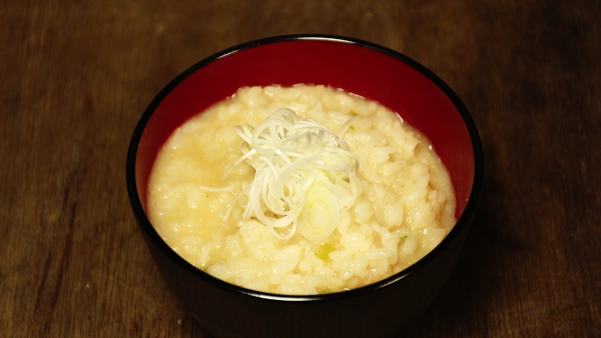 朱の椀によそったねぎ雑炊。刻みネギがのっている